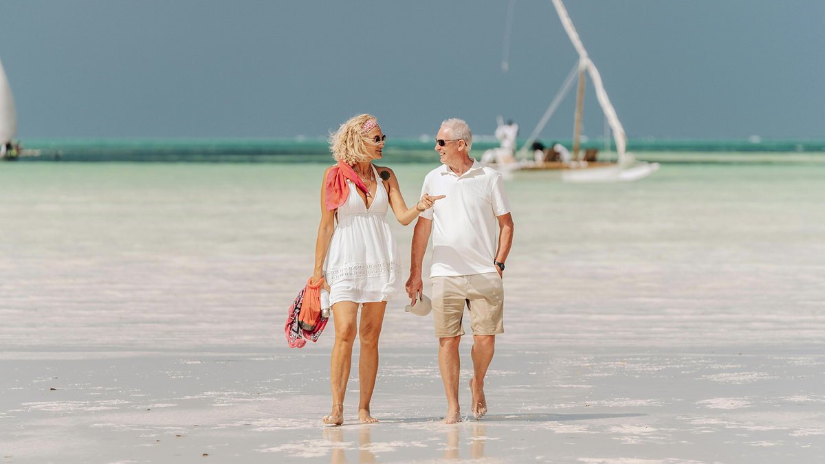 Couple walking together along a quiet Zanzibar beach at sunset