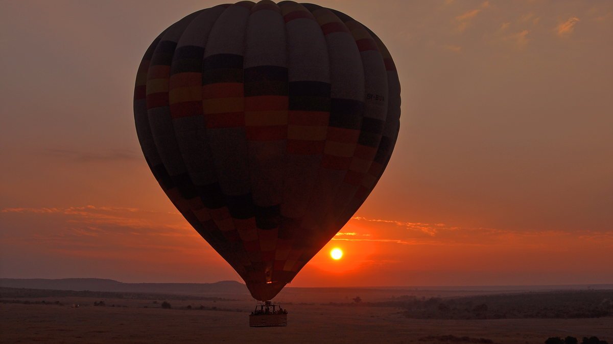 Hot air balloon rising over the Serengeti plains at sunrise