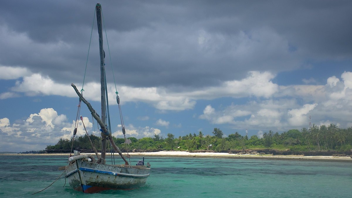 Traditional dhow moored in shallow turquoise water off Zanzibar