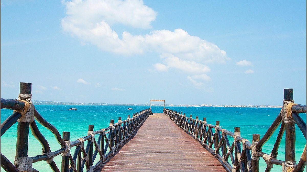 Wooden jetty reaching out into clear turquoise water on Zanzibar